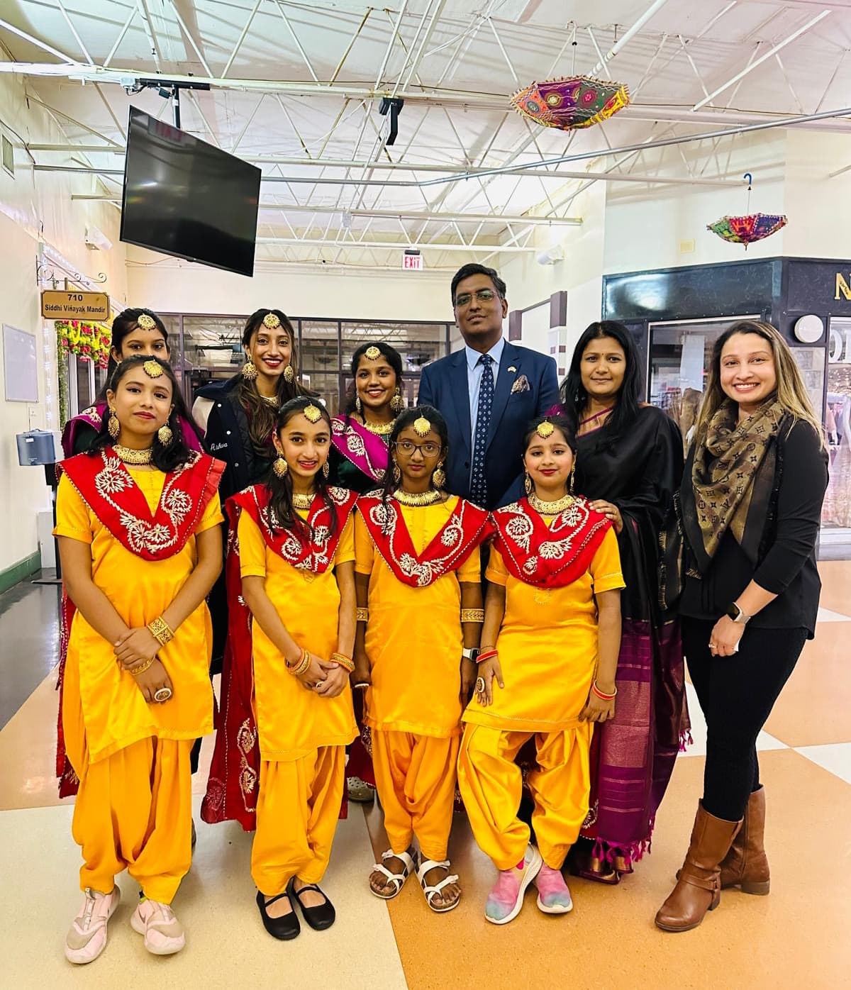 Garima Dance Academy folk-dance group in yellow and red traditional costumes, posed with the instructor