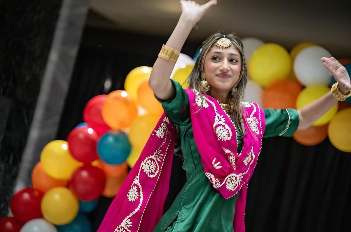 Solo Garima Dance Academy student mid-pose in pink and green traditional attire, colorful balloons backdrop