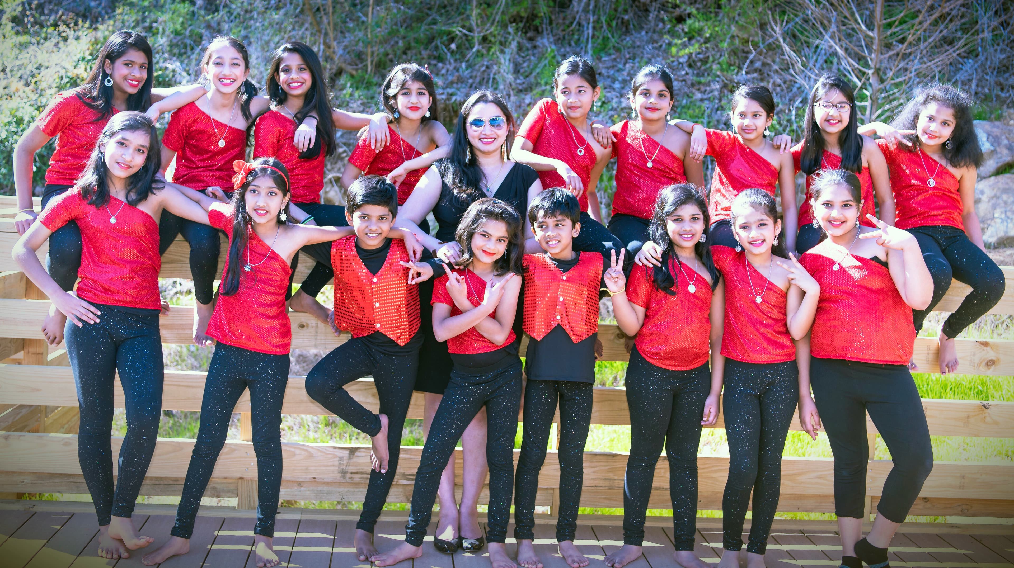 Junior class students with the instructor in matching red tops and black leggings, posed outdoors as a group